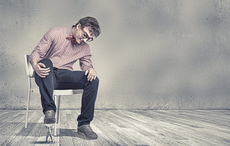 Big guy sitting on chair and stepping with foot on small one