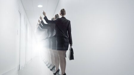 Rear view of businesswoman walking in office corridorの写真素材