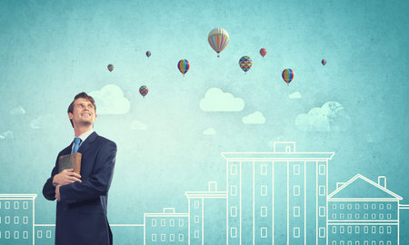 Handsome young man in suit with book in handsの写真素材