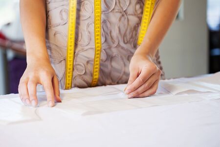 close up of dressmaker at work making patterns of fabricの写真素材