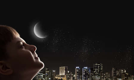 Cute boy of school age against night backgroundの写真素材