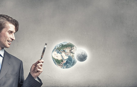 Businessman exploring Earth planet with magnifier. 
