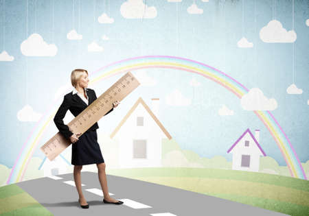 Young businesswoman measuring something with big rulerの写真素材