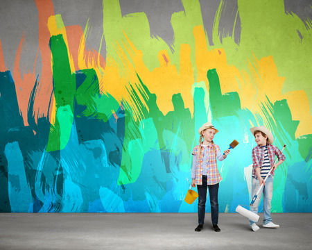 Two children of school age painting wall in colorsの写真素材