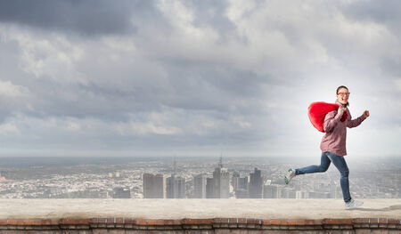 Young running girl with red santa bag in handsの写真素材