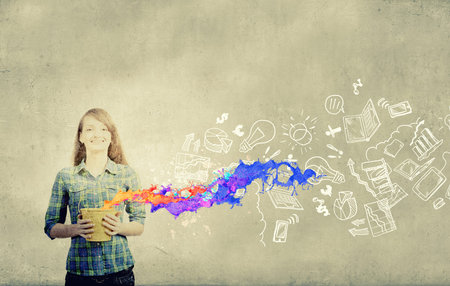 Young girl in casual splashing colorful paint from bucketの写真素材