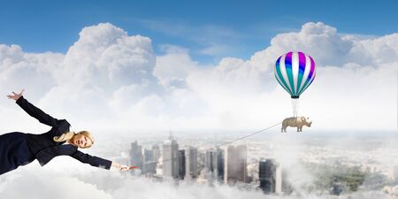 Young pretty businesswoman holding rhino on leadの写真素材