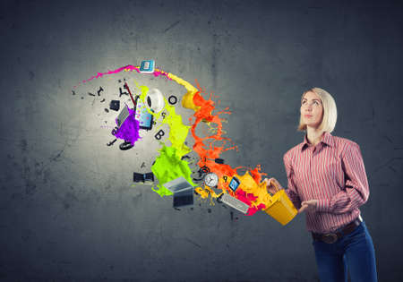 Young girl in casual splashing colorful paint from bucketの写真素材