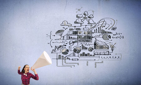 Young pretty woman screaming in paper trumpetの写真素材