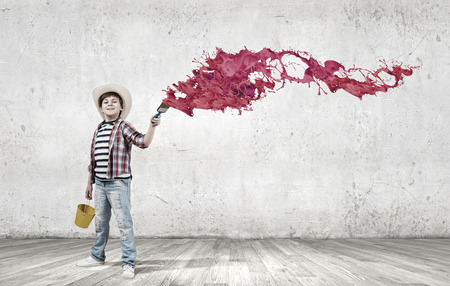 Boy of school age with yellow bucket and paint brushの写真素材