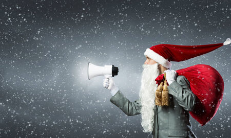 Businessman in Santa costume shouting in megaphoneの写真素材
