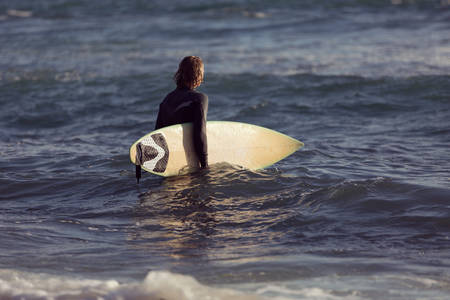 A surfer with his surfboard at the beachの写真素材