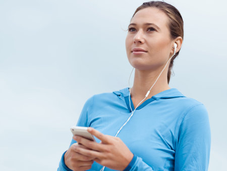 Sporty young woman with earphones on the sea coast