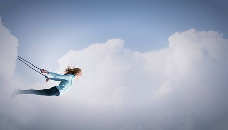 Young girl with ropes on hands trying to flyの写真素材