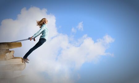 Young girl with ropes on hands trying to flyの写真素材