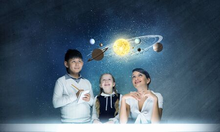 Teacher and two pupils at astronomy lesson exploring spaceの写真素材