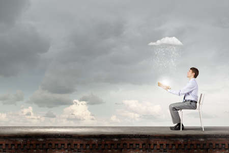 Businessman sitting in chair and reading bookの写真素材