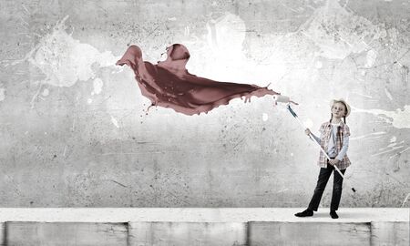 Cute girl of school age painting wall with rollerの写真素材