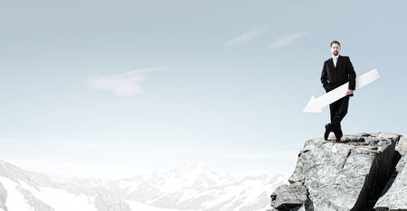 Businessman in suit holding white blank arrow in handsの写真素材