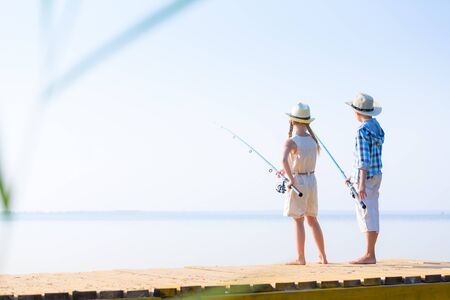 Boy and girl with fishing rods fishing together from a pierの写真素材