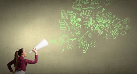 Young pretty woman screaming in paper trumpetの写真素材