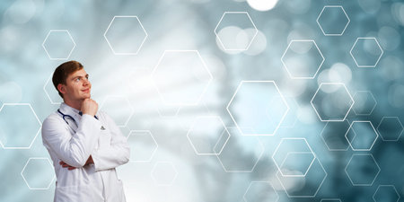 Young thoughtful male doctor on color background looking awayの写真素材