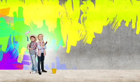 Two children of school age painting wall in colorsの写真素材