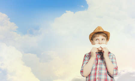 Funny cute boy trying on paper mustacheの写真素材