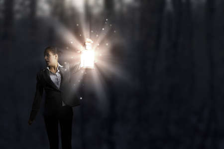 Young pretty businesswoman with lantern in darknessの写真素材