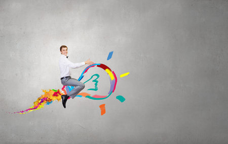 Conceptual image of young businessman riding light bulb