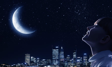 Cute girl of school age against night backgroundの写真素材