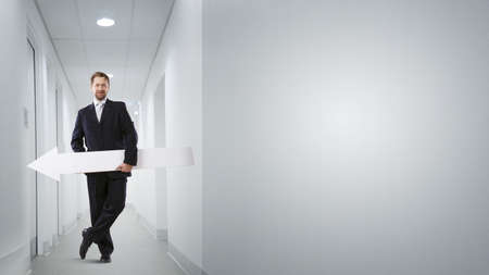 Businessman in suit with white blank arrow in handsの写真素材