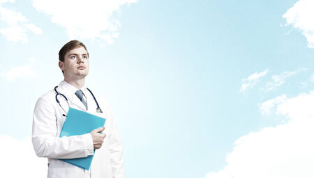 Young perspective male doctor with folder in handsの写真素材