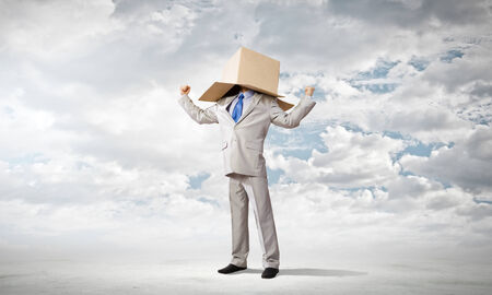 Businessman wearing carton box with drawn emotions on headの写真素材
