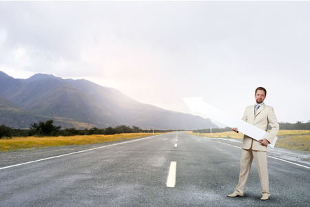 Businessman in suit with white blank arrow in handsの写真素材