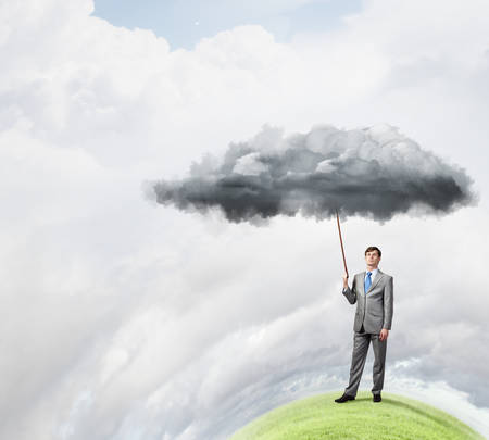 Young businessman pulling white cloud with ropeの写真素材