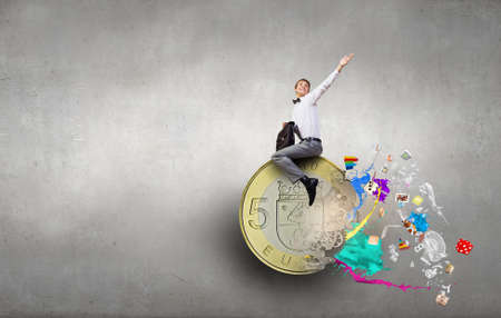 Young businessman with briefcase riding euro symbolの写真素材