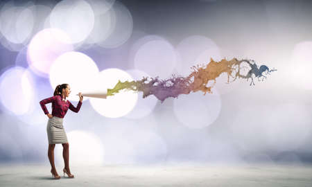 Young pretty woman screaming in paper trumpetの写真素材