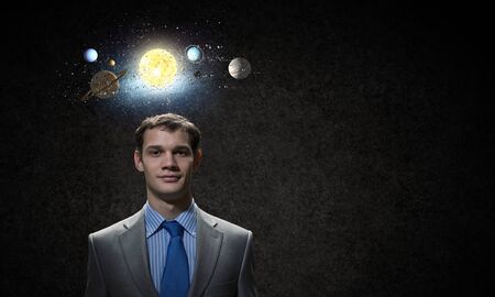 Young businessman and planets of space spinning aroundの写真素材