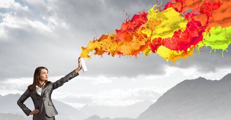 Businesswoman spraying colorful paint splashes from containerの写真素材