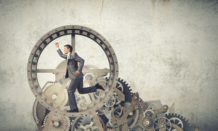 Young businessman in suit running in hamster wheelの写真素材