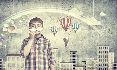 Funny cute boy trying on paper mustacheの写真素材