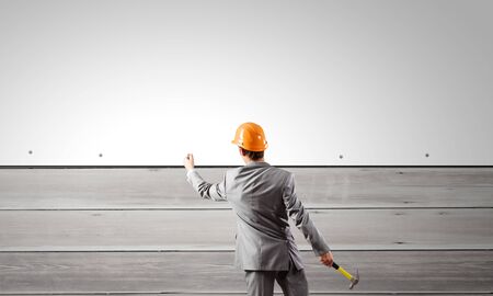 Rear view of businessman fixing white blank banner with hammerの写真素材