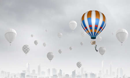 Businessman flying on aerostat balloon high in skyの写真素材