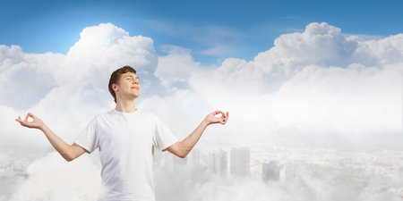 Young smiling guy sitting in lotus pose and meditatingの写真素材