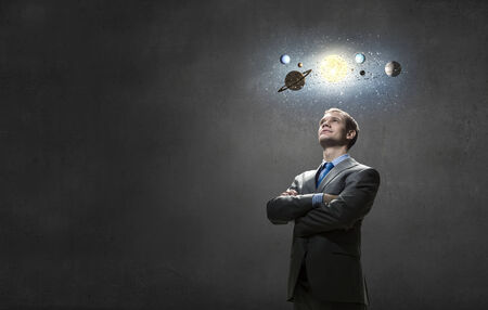 Young businessman and planets of space spinning aroundの写真素材