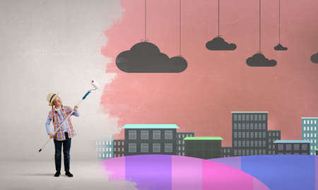 Cute girl of school age painting wall with rollerの写真素材