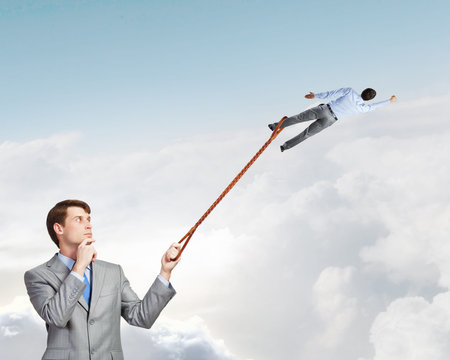 Businessman holding on lead another escaping businessman
