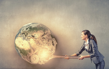 Young businesswoman fixing gears mechanism with wrench. Elements of this image are furnished by NASAの写真素材