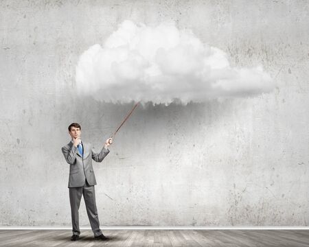 Young businessman pulling white cloud with ropeの写真素材